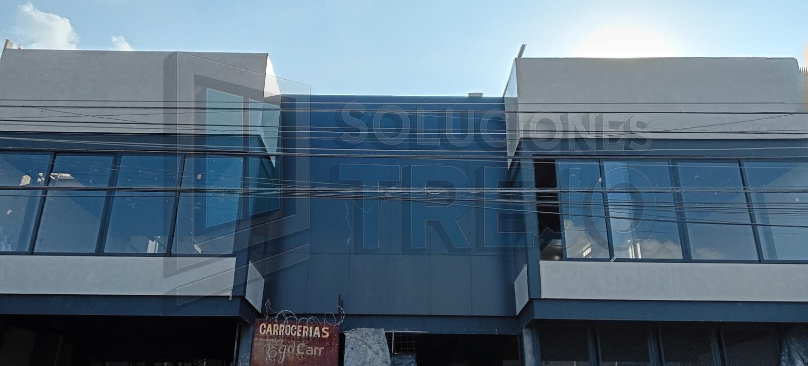 Imagen de fachada moderna con paneles de aluminio negro mate y ventanales de cristal templado, instalación profesional en Guadalajara.